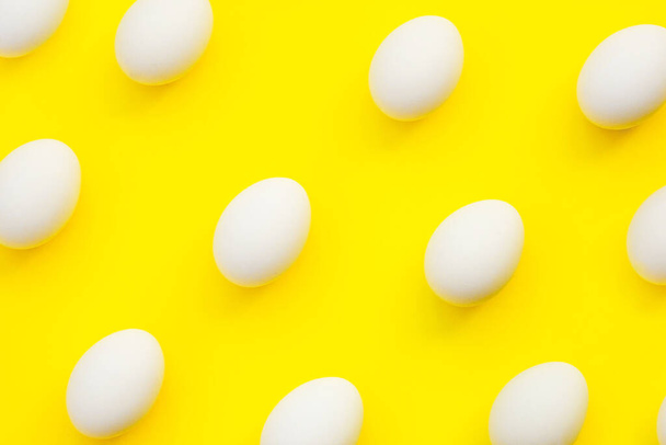 Minimalism style. Flat eggs lay image raw on colored yellow background, Pattern of white chicken eggs on yellow background, top view, flat lay copy space. Creative food minimalistic background, Easter - Foto, imagen