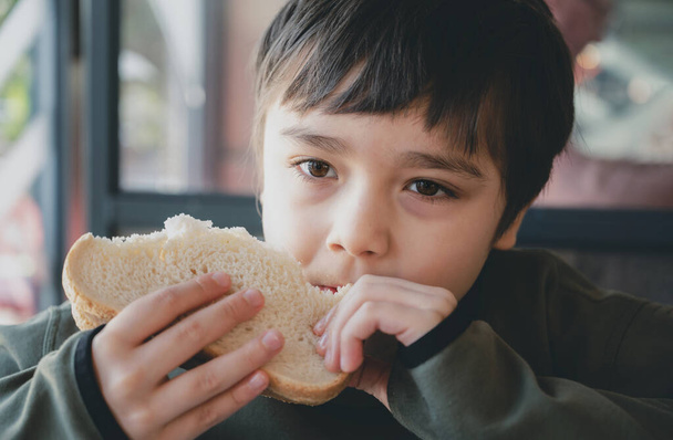 Πορτρέτο υγιή νεαρό αγόρι τρώει σάντουιτς μπέικον, Παιδί σχολείο έχοντας πρωινό στο καφέ είναι για να πάει στο σχολείο, Παιδί bitting τοστ σάντουιτς βοείου κρέατος cheddar τυρί για το μεσημεριανό γεύμα. - Φωτογραφία, εικόνα