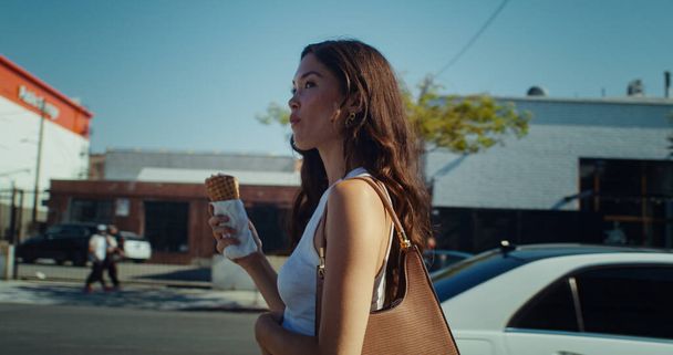 Caddede dondurma tatmaya giden çekici bir kız. Tatlıyı yalayan Asyalı kadın - Fotoğraf, Görsel
