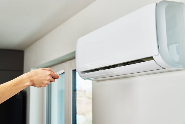 Hand adjusting temperature on air conditioner - Foto, Bild