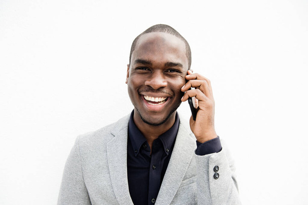 Portrait en gros plan d'un homme d'affaires afro-américain souriant parlant avec son téléphone portable sur fond blanc isolé - Photo, image