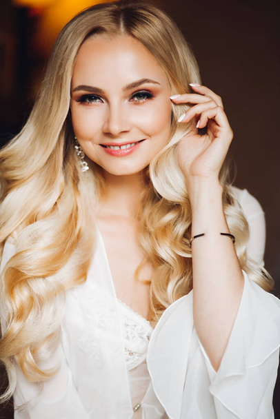 Beautiful blondie bride smiling at camera posing at bedroom. - 写真・画像
