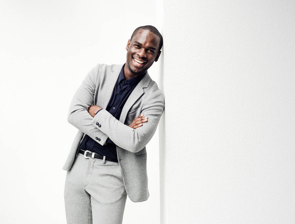 白い壁に寄りかかって腕を組んで幸せなアフリカ系アメリカ人ビジネスマンの肖像画 - 写真・画像