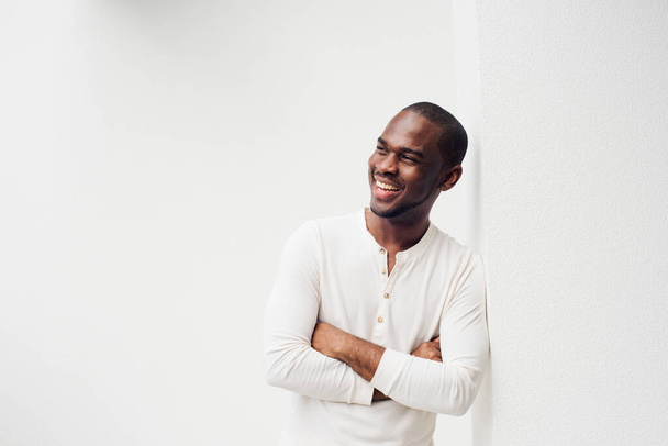 Retrato del guapo hombre afroamericano sonriente con los brazos cruzados sobre fondo blanco  - Foto, imagen