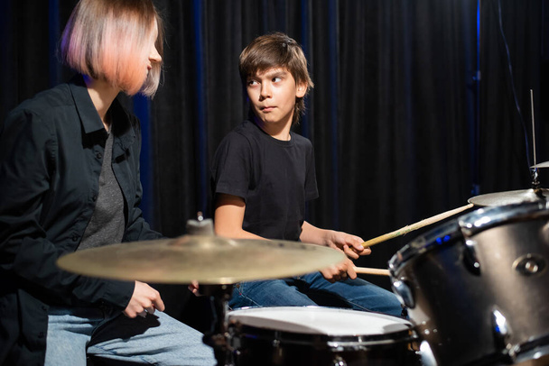 Young woman teaching boy to play drums. - Fotoğraf, Görsel