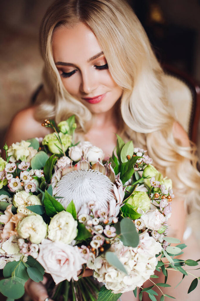 Pretty bride holding wedding bouquet and posing with closed eyes. - Fotó, kép