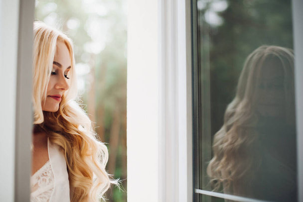 Gorgeous blondie bride walking at balcony and waiting for her groom. - Foto, afbeelding