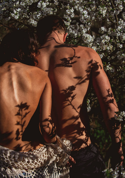 Sensual couple in cherry bloom. Naked woman man in love in blossoming spring tree flower. Romance, relationship, nature, environment concept. - Valokuva, kuva