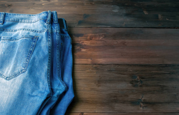 Blue Jeans auf braunem Holzgrund. Ausgefranste Jeans auf rauer Holzoberfläche. - Foto, Bild