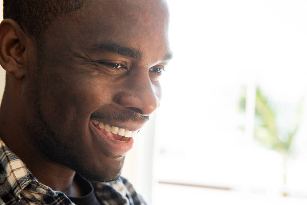 Κοντινό πορτραίτο Αφροαμερικανός που γελάει και κοιτάζει αλλού. - Φωτογραφία, εικόνα