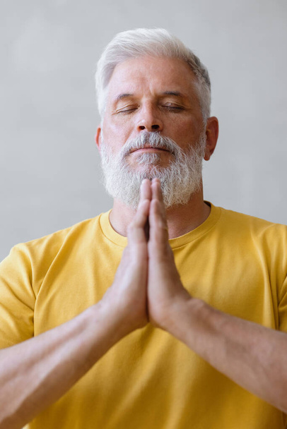 hombre con el pelo gris medita y hace ejercicios de respiración. fitness deportivo y ejercicios físicos para las personas mayores - Foto, imagen