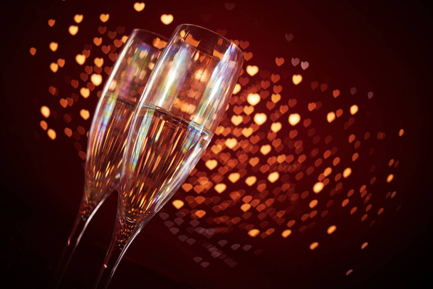 Two champagne glasses in front of romantic red heart bokeh background. Valentines day celebration background - Foto, Bild