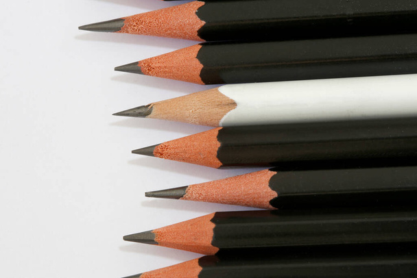 Bílá tužka ve skupině černé tužky zarovnány, jejich význačným rozdíl a rozmanitost - Fotografie, Obrázek