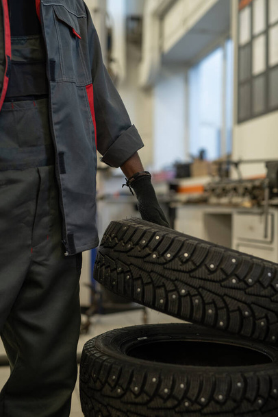 Mechanic Holding Tire in Workshop - Photo, image