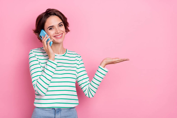 Portrait of attractive cheerful girl holding on palm copy space d advert talking on phone isolated over pink pastel color background - Φωτογραφία, εικόνα