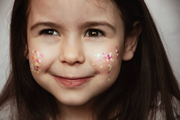Portrait of a child girl with sequins on her cheeks - Foto, afbeelding