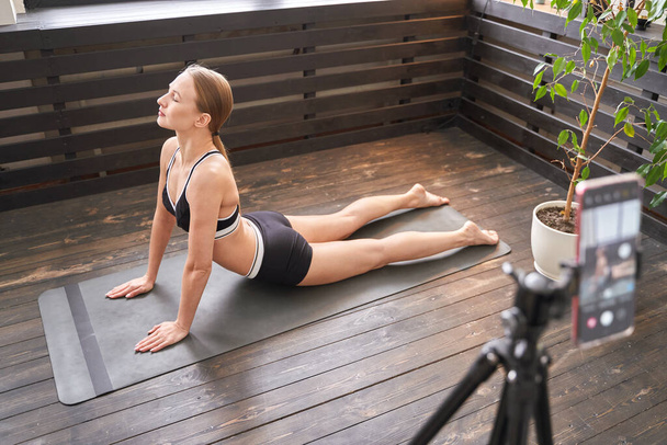 Evde yoga egzersizi yapan genç bir kadın. Çevrimiçi sağlık dersleri. Kapalı - Fotoğraf, Görsel