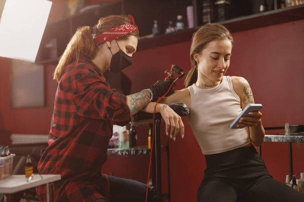 Muotokuva nainen tatuointi taiteilija tekee tatuointi naispuolinen asiakas - Valokuva, kuva