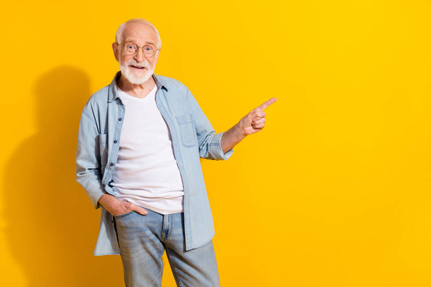 Portrait of attractive cheerful grey-haired man demonstrating copy space ad isolated over bright yellow color background - Photo, image