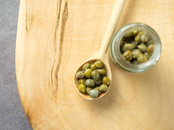 Pickled nebo marinované zelené kapary na dřevěné lžíce zblízka, selektivní zaměření - Fotografie, Obrázek