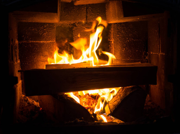 Brennendes Brennholz im Kamin eines Landhauses. Rustikaler Ofen mit brennenden Holzscheiten in Großaufnahme. - Foto, Bild