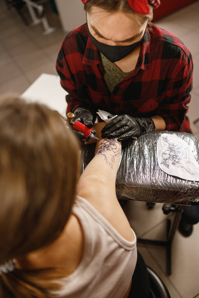 Κάθετη φωτογραφία του τατουάζ καλλιτέχνη μελάνι τατουάζ στο βραχίονα - Φωτογραφία, εικόνα