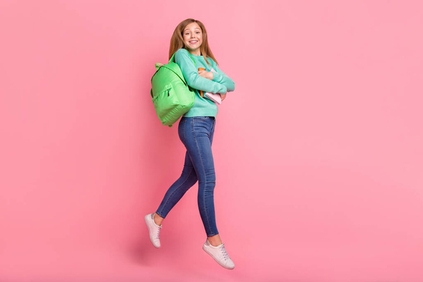 Photo of excited girl wear turquoise sweater jumping walking hugging school supplies isolated pink color background - Foto, Imagen