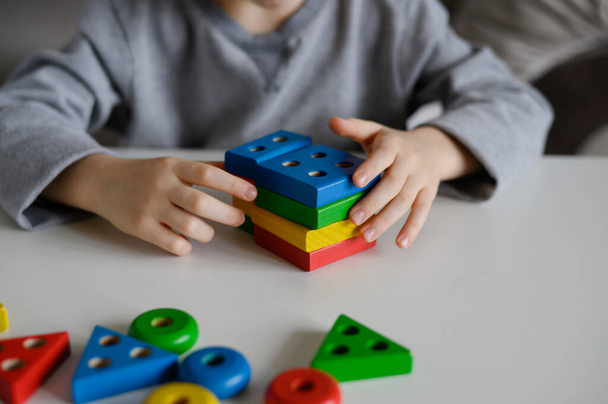 Un enfant joue avec un jouet éducatif en bois coloré. Jouet en bois pour enfants - Photo, image