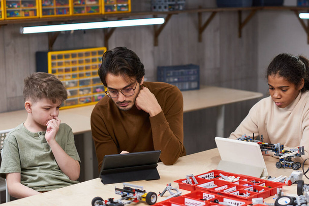 Männlicher Lehrer hilft Jungen im Robotikunterricht - Foto, Bild
