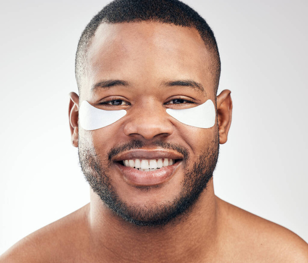 These patches provide deep hydration. Studio portrait of a handsome young man wearing under-eye patches against a white background. - Foto, Imagen