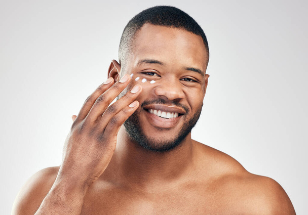 Restore and enrich your skin. Studio portrait of a handsome young man applying moisturiser to his face against a white background. - Foto, Imagem