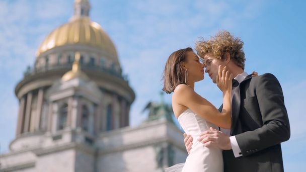Wedding photo shoot. Action. A couple poses next to St. Isaac s Cathedral , a young man with long curly hair and his bride with bare shoulders and long earrings - Foto, Imagem