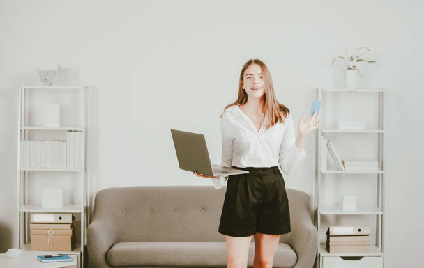 Young businesslady with laptop and credit card at workplace in the office. Secretary woman in formal wear working on project at modern office. - Zdjęcie, obraz