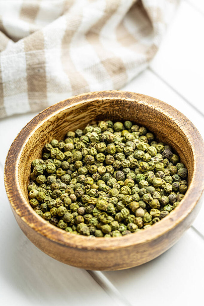 Dried green peppercorn. Dry green pepper spice in bowl on a white table. - Foto, afbeelding