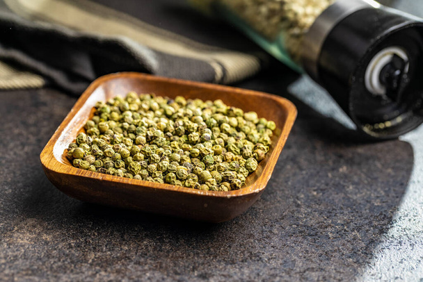 Dried green peppercorn. Dry green pepper spice in bowl on a black table. - Foto, afbeelding