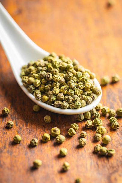 Dried green peppercorn. Dry green pepper spice in spoon on a wooden table. - Foto, afbeelding