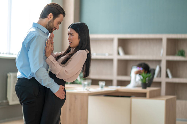 Man behaving improperly with his female colleague in the office - Photo, image