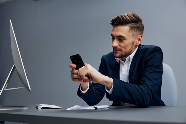 Όμορφος άντρας επιχειρηματική συνομιλία στο τηλέφωνο λειτουργεί μπροστά από ένα στέλεχος υπολογιστή - Φωτογραφία, εικόνα