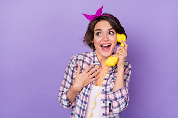 Photo of excited funny woman wear plaid shirt talking phone looking empty space isolated violet color background - Zdjęcie, obraz