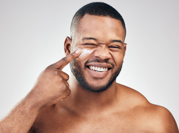 Pick up a good moisturiser for healthy skin. Studio portrait of a handsome young man applying moisturiser to his face against a white background. - Foto, Bild