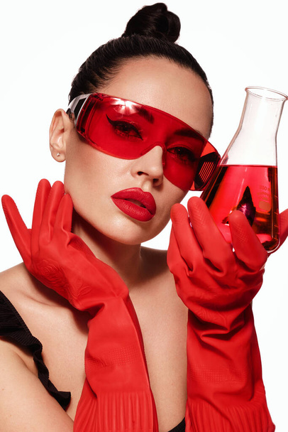 Beautiful woman with laboratory containers with red liquid, make-up and hairstyle. Beauty face. - Foto, imagen