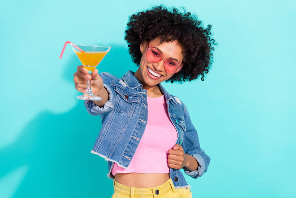 Photo of cute funky young lady dressed denim jacket glasses inviting you drink beverage isolated teal color background - Fotografie, Obrázek