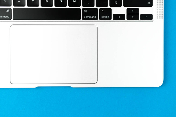 ノートパソコンのキーボードフラット青の背景を置く。オフィスワークスペーステーブル、最小限のデザインコンセプト。トップビュー、コピースペース - 写真・画像