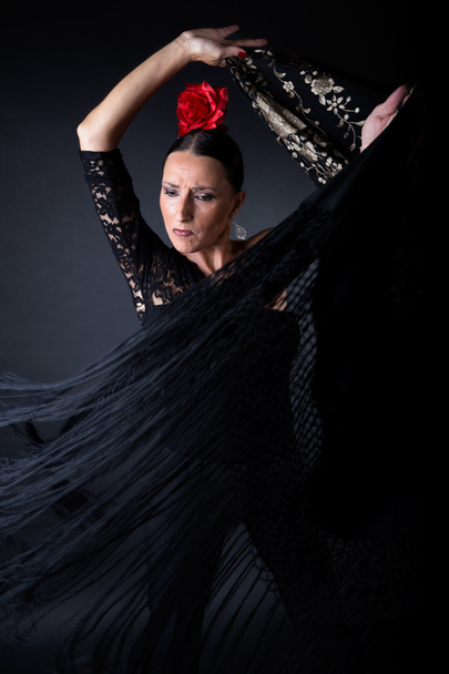Young flamenco dancer in beautiful dress on black background. - Foto, afbeelding