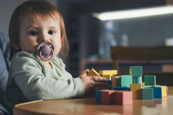 Baby girl playing with block toys iat home while looking at camera. Fun learning. Children education. Wooden toys. - Φωτογραφία, εικόνα