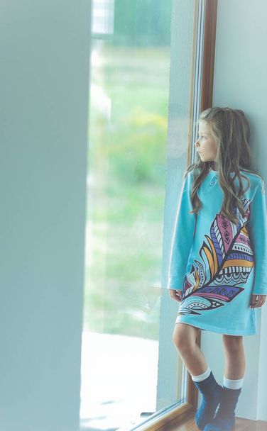 The beautiful girl stands near the large window filled with light - Photo, image
