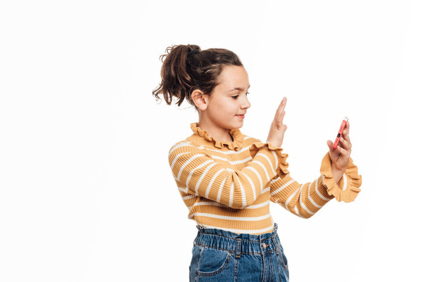 Dziewczyna machająca ręką wita się z kimś podczas nagrywania filmu lub rozmowy wideo przez telefon komórkowy. - Zdjęcie, obraz
