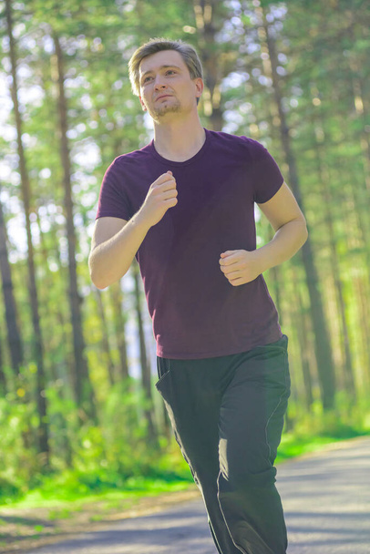 Man jogging in city partk at beautiful summer day. Sport fitness model caucasian ethnicity training outdoor. - Photo, Image