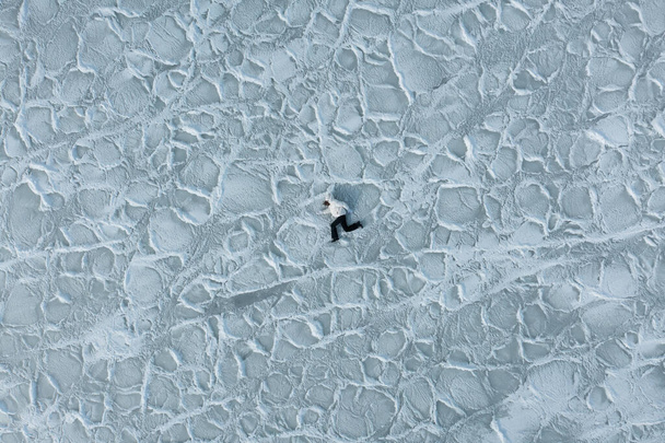 Το κορίτσι τρέχει στην παγωμένη υφή του πάγου. Θέα στη θάλασσα από ψηλά σε παγωμένη υφή θαλασσινό νερό. Το χειμώνα, η θάλασσα πάγωσε, μετατρέποντας σε ένα παγωμένο πεδίο από παγωμένα άρματα πάγου. Ιστορικό κατεψυγμένων παγετώνων. - Φωτογραφία, εικόνα