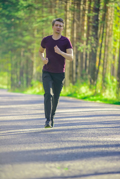 Man jogging in city partk at beautiful summer day. Sport fitness model caucasian ethnicity training outdoor. - Fotó, kép